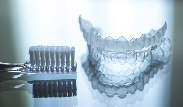 toothbrush next to an Invisalign tray