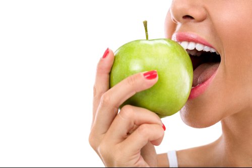 Woman with straight white teeth biting into an apple
